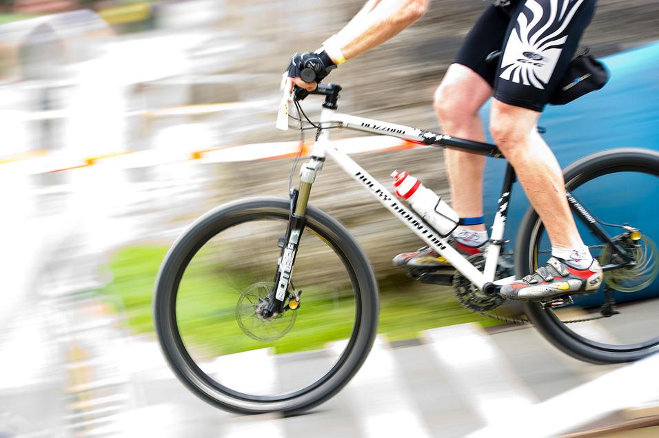 Radsportler fährt mit einem Mountainbike auf einem unebenen Terrain, Wasserflasche am Rahmen, schnelle Bewegung.